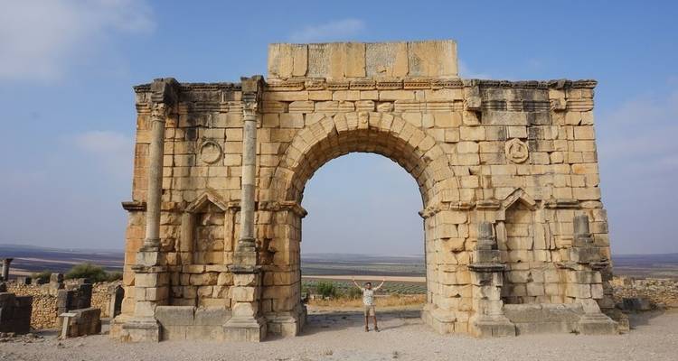 Eine Person, die unter einem historischen Steinbogen steht.