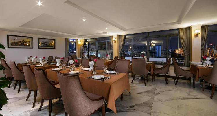 Elegante área de comedor con mesas puestas y vista a la ciudad.