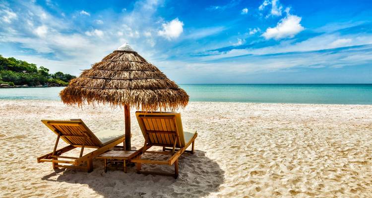 Beach with sunloungers and umbrella overlooking the ocean