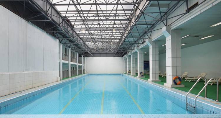 Hallenbad mit klarem blauen Wasser und Liegestühlen.