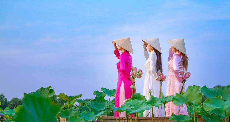 Women in traditional Vietnamese attire holding lotus flowers.