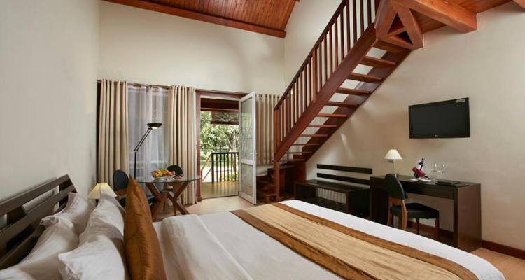 Hotelkamer met een bed, bureau en trap naar de bovenverdieping.