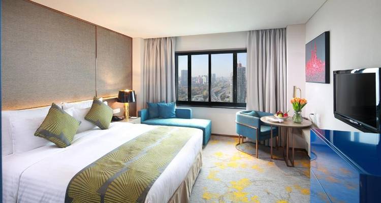 Moderne hotelkamer met een kingsize bed en stadsuitzicht.