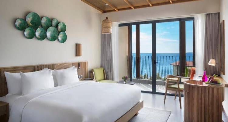 Luxe hotelkamer met balkon met uitzicht op zee en moderne inrichting.