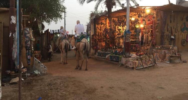 Mensen die op kamelen door een marktgebied rijden.