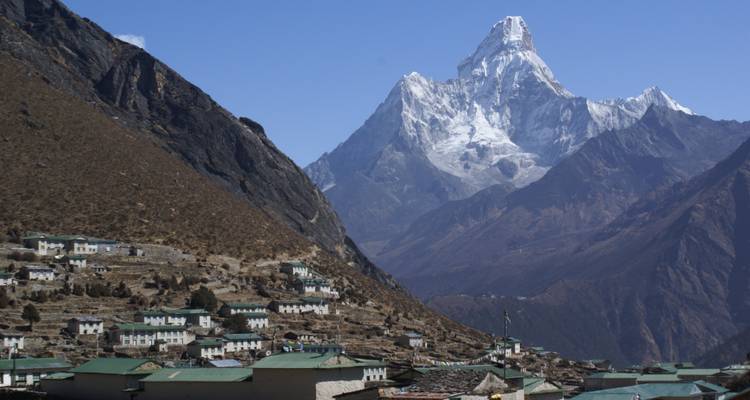 Un village de montagne avec des sommets enneigés à l'arrière-plan.