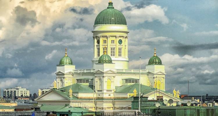 Cathédrale ornée avec plusieurs dômes verts sous un ciel nuageux.
