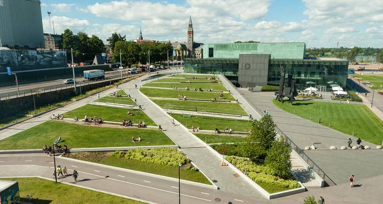 Grand parc avec pelouses entretenues et allées dans un environnement urbain.