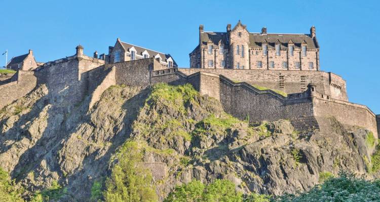 El Castillo de Edimburgo encaramado en una colina rocosa en un día despejado.