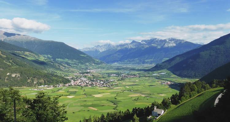 Vue de Burgeis avec des champs verts et des montagnes.