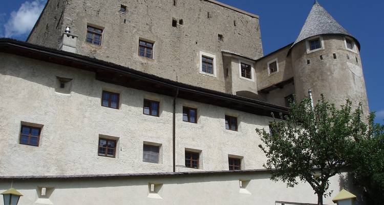 Un château historique avec des tours et des murs en pierre sous un ciel bleu.