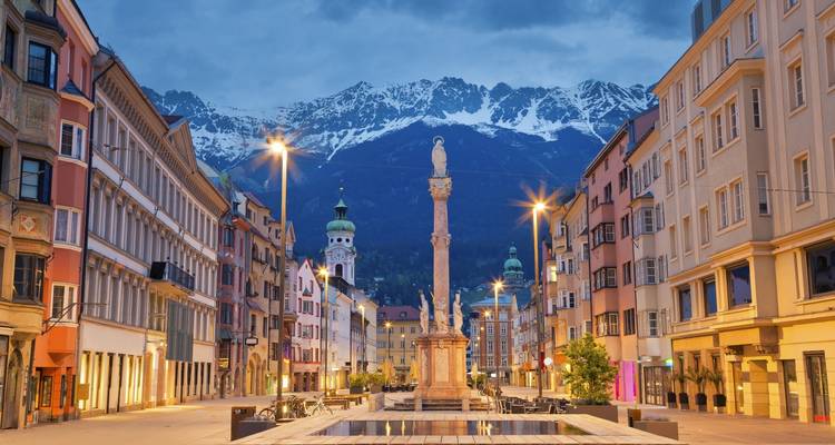 Vue de rue d'Innsbruck avec des montagnes enneigées au loin.