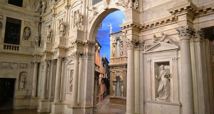 Vue intérieure d'un théâtre orné avec des colonnes détaillées et des statues.