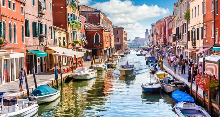 Canal animé bordé de bâtiments colorés et de nombreux bateaux.