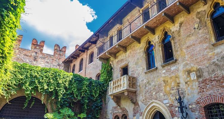Bâtiment historique avec des murs couverts de lierre et un petit balcon.
