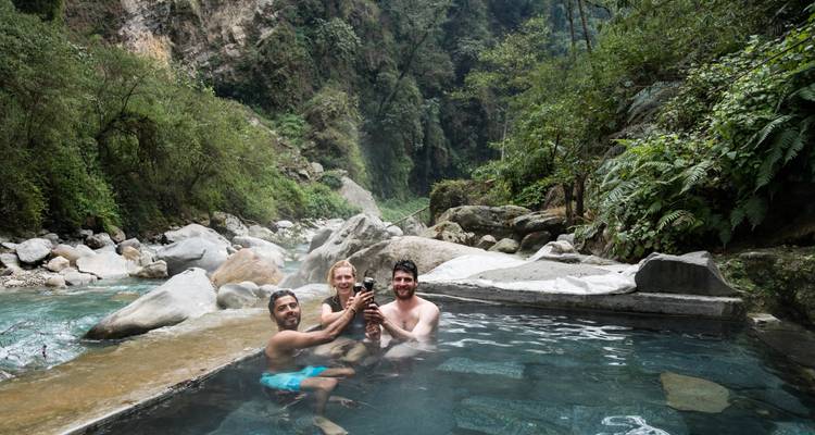 Des gens dans une source chaude naturelle entourée de forêt.