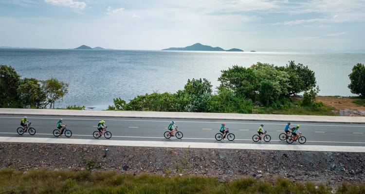Des cyclistes roulant le long d'une route côtière avec des îles en arrière-plan.