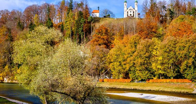 Église sur une colline dans une forêt d'automne au bord d'une rivière.