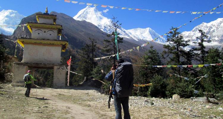 Trekkers near a mountain village with prayer flags.