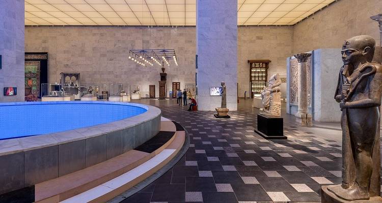 Grand intérieur de musée avec des statues et des visiteurs.
