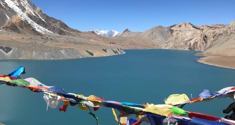 Vista del lago con montañas y coloridas banderas de oración.
