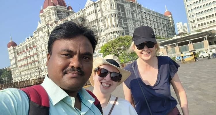 Drie mensen die glimlachen voor een historisch hotel