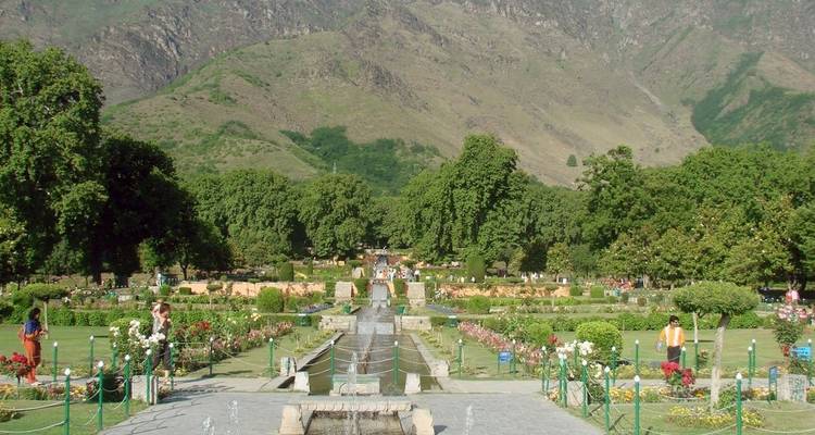 Schöner Garten mit Springbrunnen und Blumenarrangements vor Bergen.