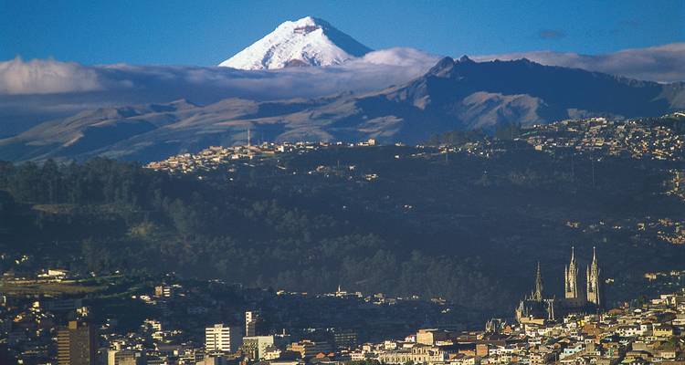 Ville de Quito avec une montagne enneigée en arrière-plan.