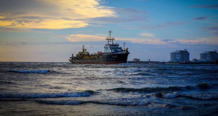 Barco industrial en el océano durante la puesta de sol.