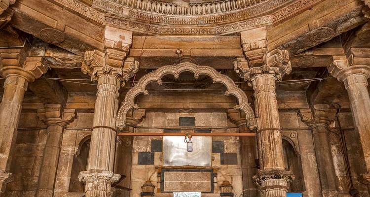 Stone columns and intricately carved arch inside a historic Indian temple or stepwell