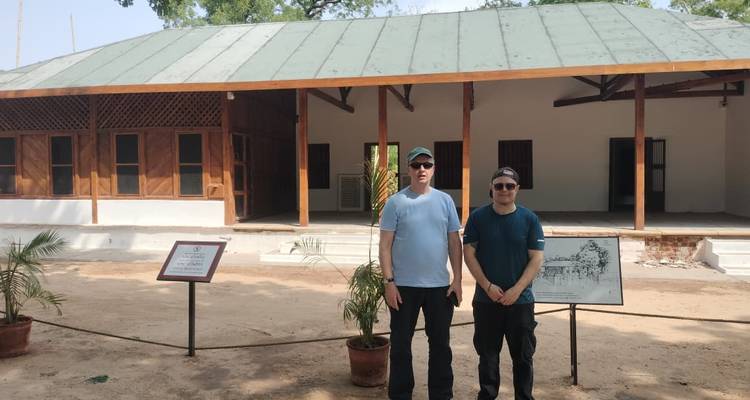 Two men standing in front of a restored wooden building at Gandhi Ashram