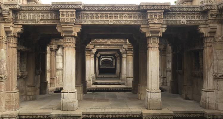 Symmetrical stone corridor with repeating carved pillars leading into the distance