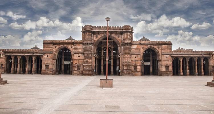 Wide courtyard of Jama Masjid with dramatic cloudy sky overhead