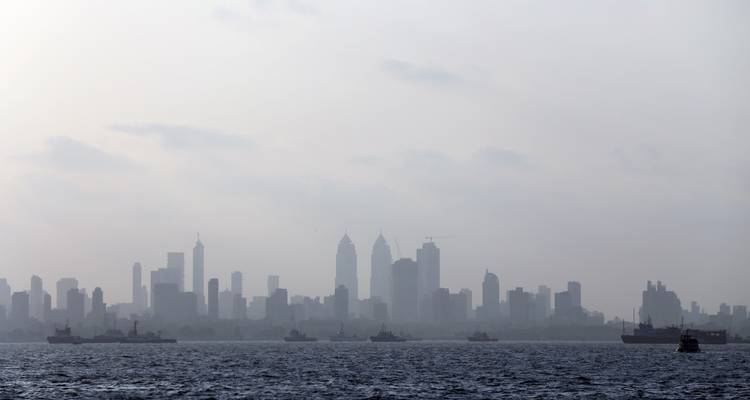 Dunstiger Horizont einer Großstadt mit Booten auf dem Wasser.