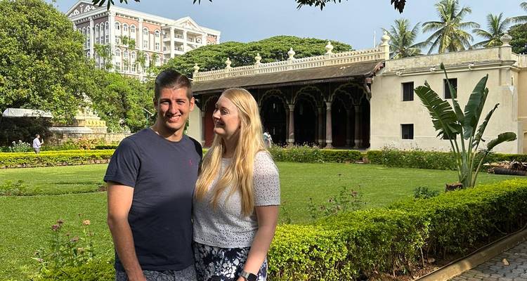 Couple posant devant un bâtiment orné avec un jardin.