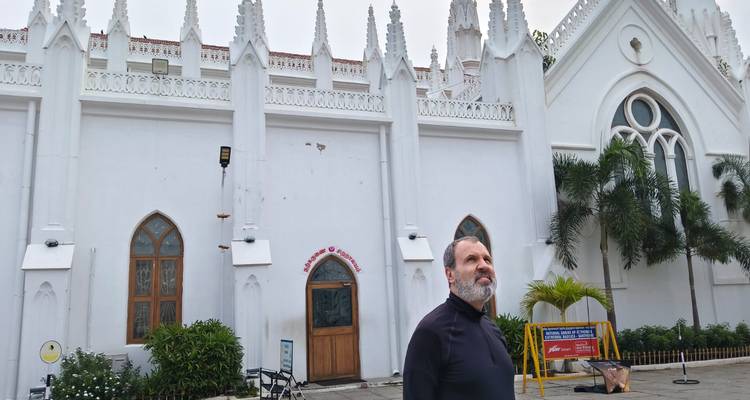 Persona de pie afuera de una catedral blanca de estilo gótico.