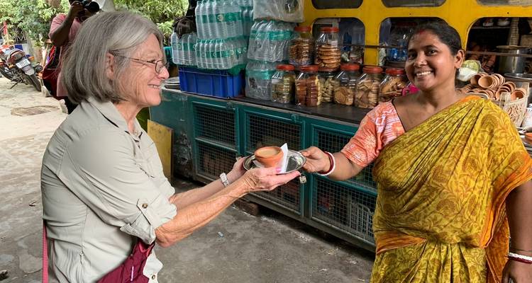 Mujer recibiendo una taza de barro con té de un vendedor.