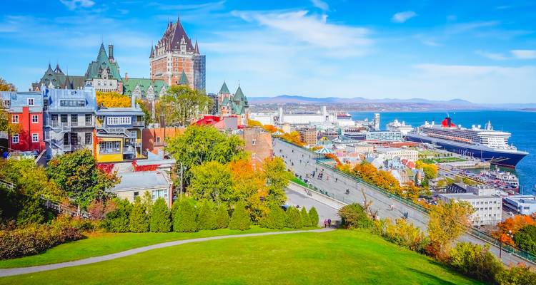 Vibrant autumn panorama of Quebec City with Château Frontenac overlooking the St. Lawrence River and a docked cruise liner.