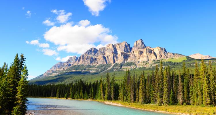 Castle Mountain’s rugged limestone peaks towering over the turquoise Bow River and dense pine forest.