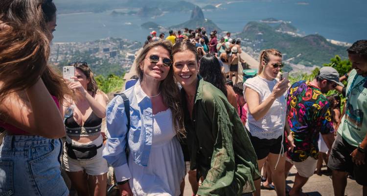 Dos mujeres sonriendo con una vista panorámica de Río de Janeiro al fondo.