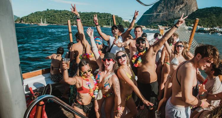 Personas celebrando en un barco con una vista panorámica del agua y la ciudad.