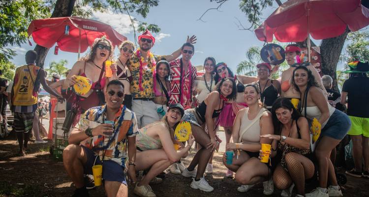 Grupo de personas con vestimenta colorida celebrando al aire libre bajo sombrillas rojas.