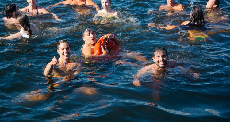 Viajeros nadando y jugando en aguas del mar azul profundo alrededor de un bote