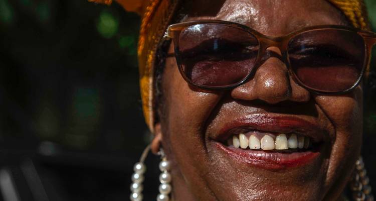 Une personne souriante portant des lunettes et un foulard.