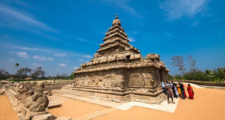Antiguo templo de piedra con tallados intrincados y unas pocas personas con vestimenta colorida.