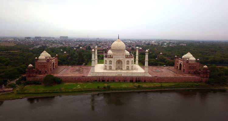 Vista aérea del Taj Mahal junto a un río, rodeado de vegetación.