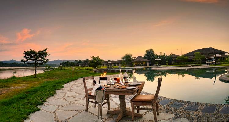 Beautiful outdoor dining setup by a pool at sunset.