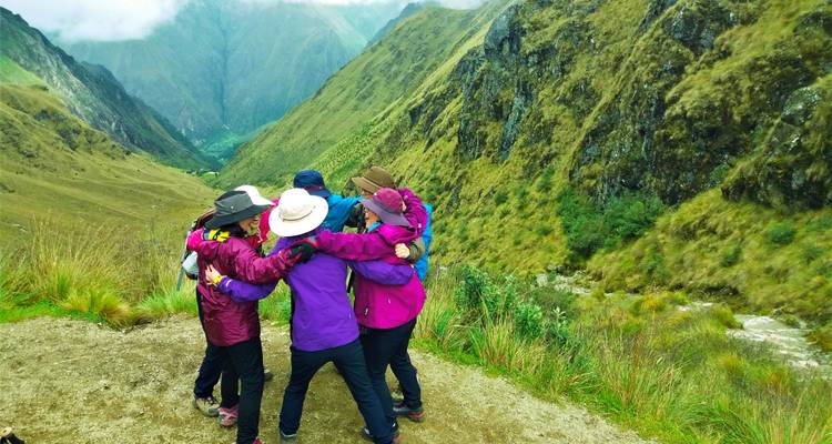 Groep wandelaars die elkaar omhelzen met uitzicht op de bergen.