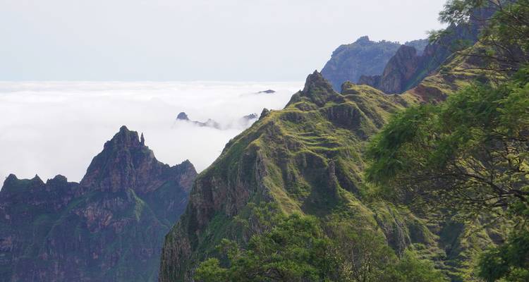 Dramatische Berggipfel mit grünen Landschaften und Wolken.