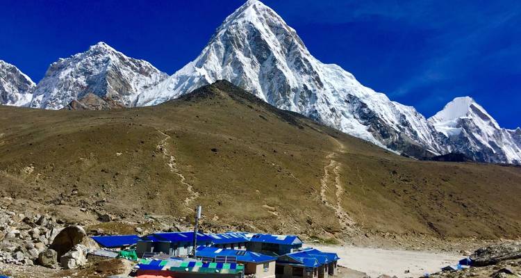 Mountain with snow peaks and a small settlement with colorful roofs.